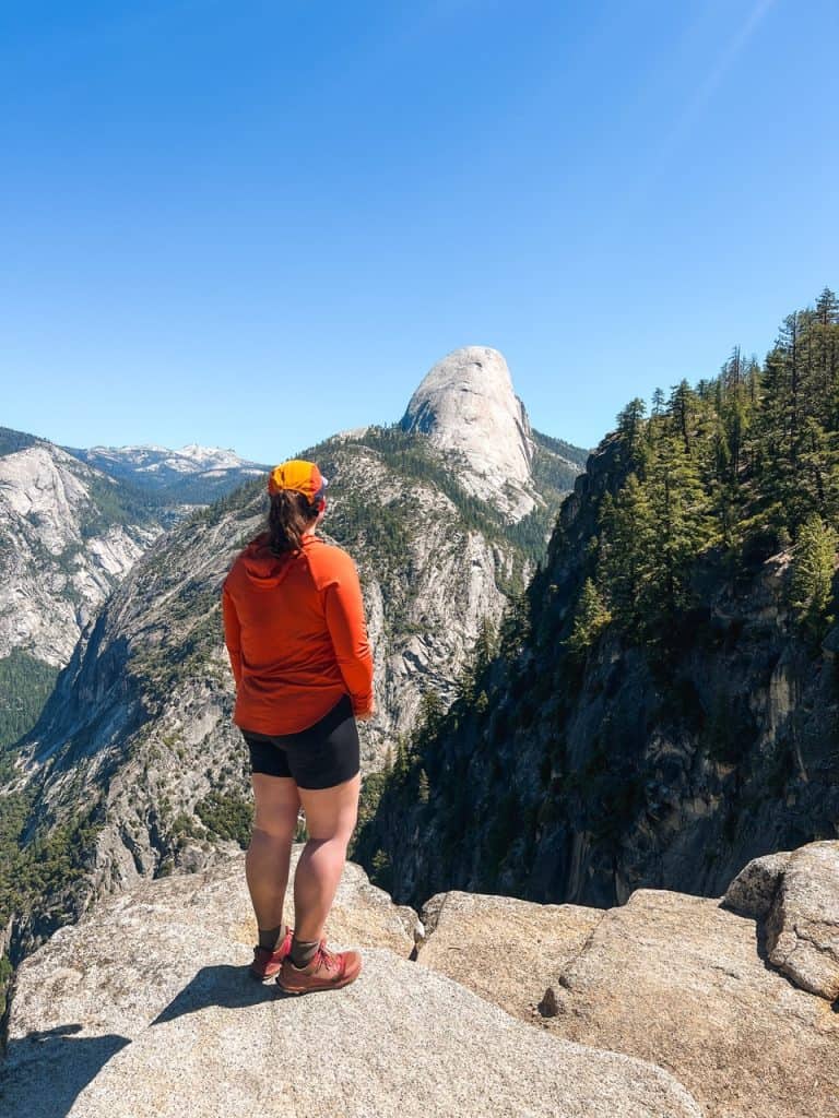 woman hiker standing on ledge looking out at mountains