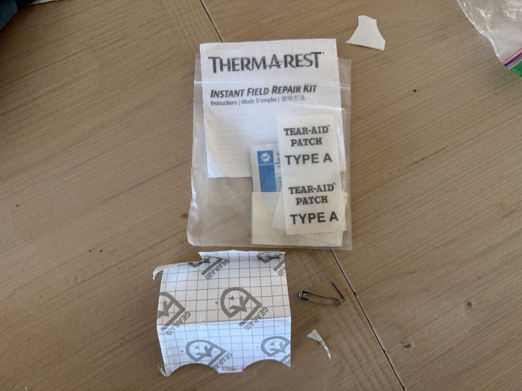 Therm-a-Rest instant field repair kit and gear aid tape, plus a safety pin and needle in a repair kit.