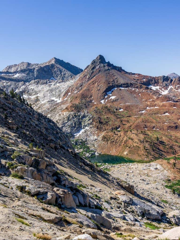 Mountain landscape with rugged rocky slopes and a bright blue sky, showcasing the beauty of backcountry.