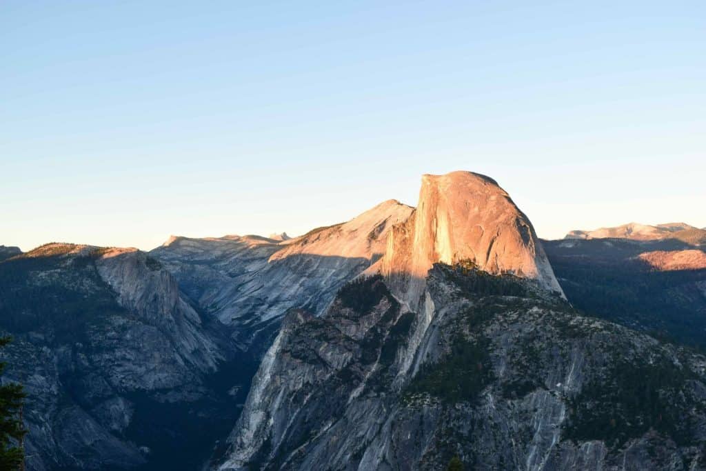 Half Dome partially glowing in pink alpenglow from Glacier Point