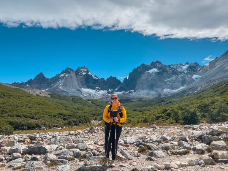 Hiking in the mountains with a backpack, surrounded by alpine scenery and rugged peaks under a bright blue sky.