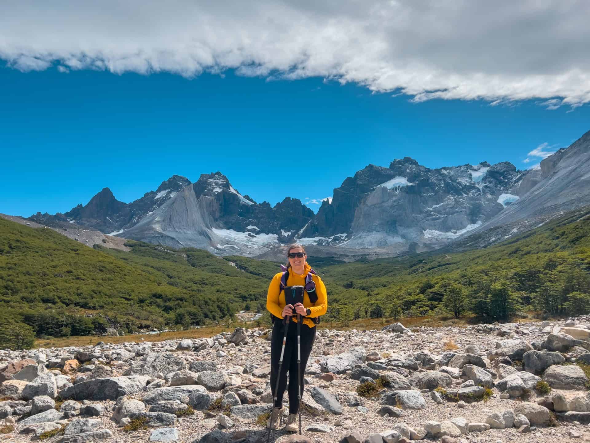 Hiking in the mountains with a backpack, surrounded by alpine scenery and rugged peaks under a bright blue sky.