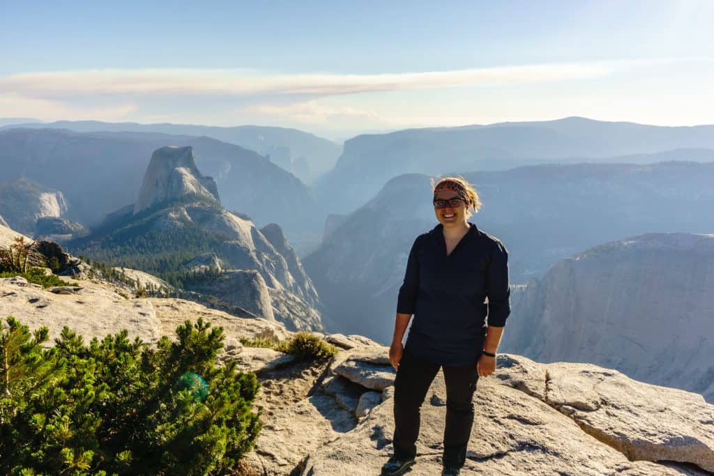 author Emily standing on clouds rest with Half Dome in the distance