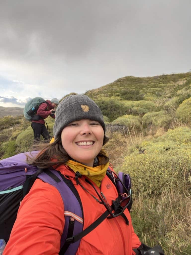 author Emily dressed in backpacking gear, rain jacket, fleece, beanie