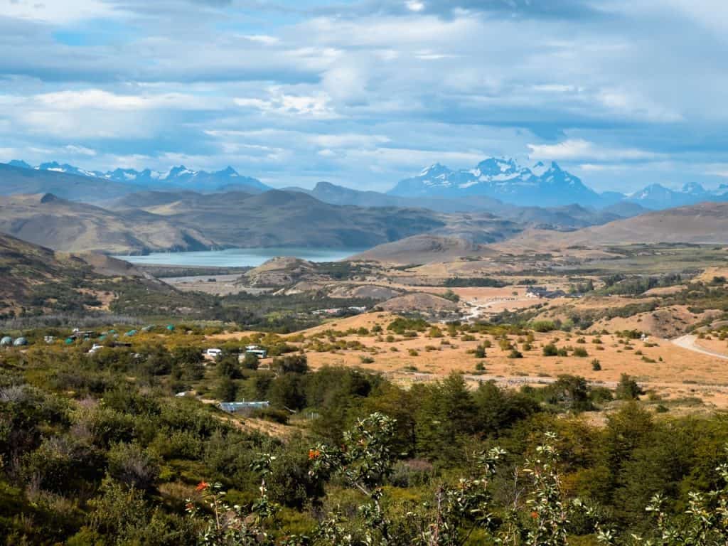 Breathtaking mountain landscape with lake, rolling hills, and distant snow-capped peaks in Torres del Paine