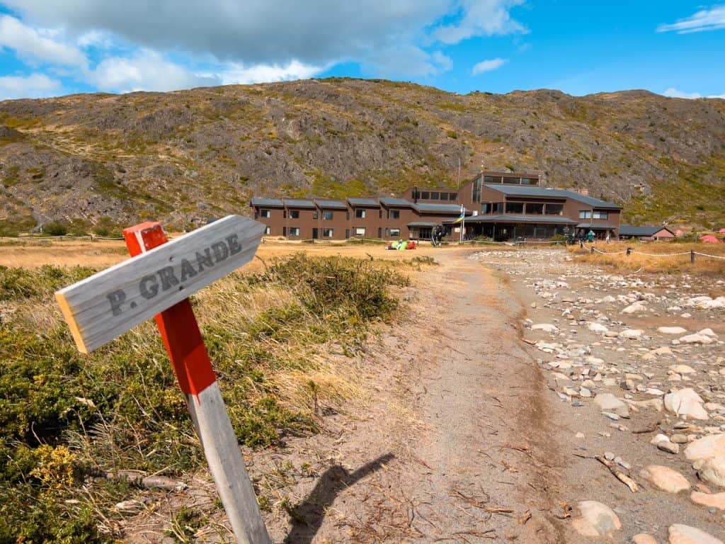 Outdoor mountain lodge with rocky trail, scenic landscape, and rustic signage at P. Grande.