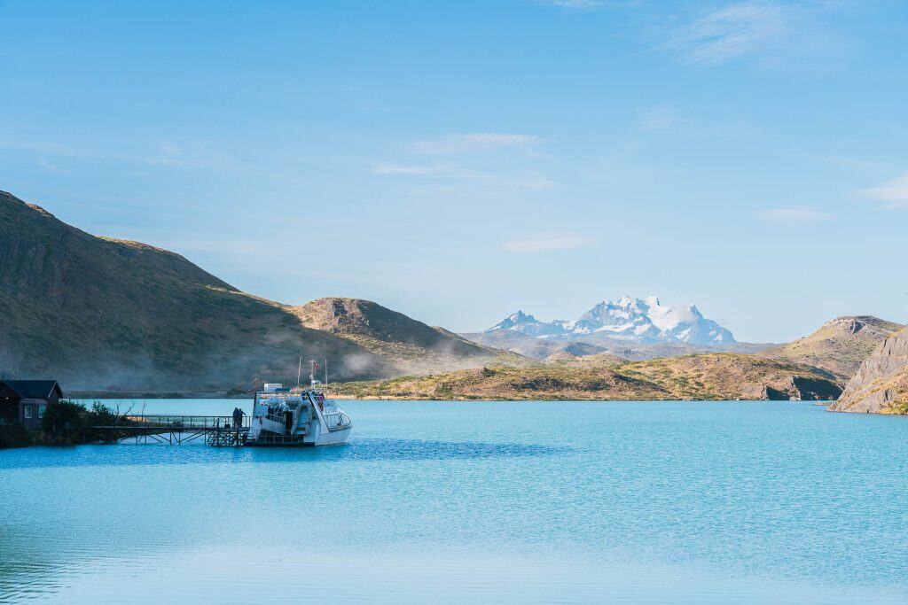 boat at dock on glacier blue lake with a mountain ridge in the distance