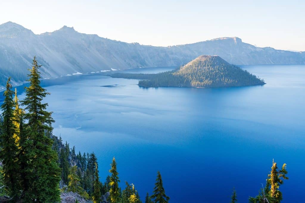 Pristine mountain lake with forested islands and surrounding peaks, stunning wilderness scenery.