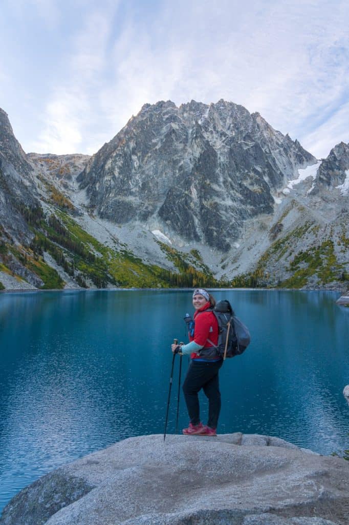 Woman hiking in a mountain lake with backpack and trekking poles, scenic outdoor adventure colchuck lake washington.