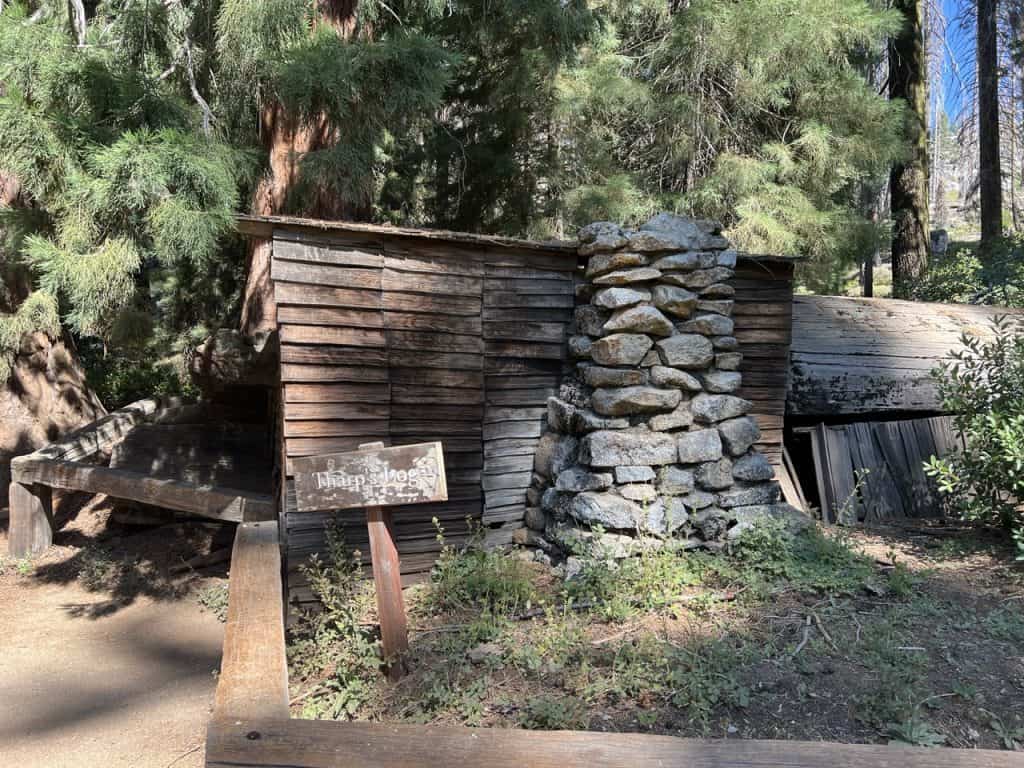 a sign reading Tharp's log in front of a fallen sequoia tree that was converted into a home in the 1800s.