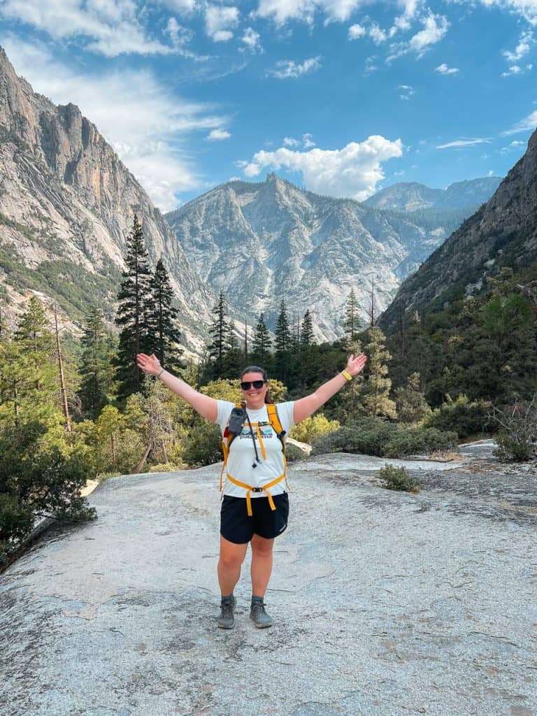 Woman hiking in Sequoia National Park with mountains and trees in background.