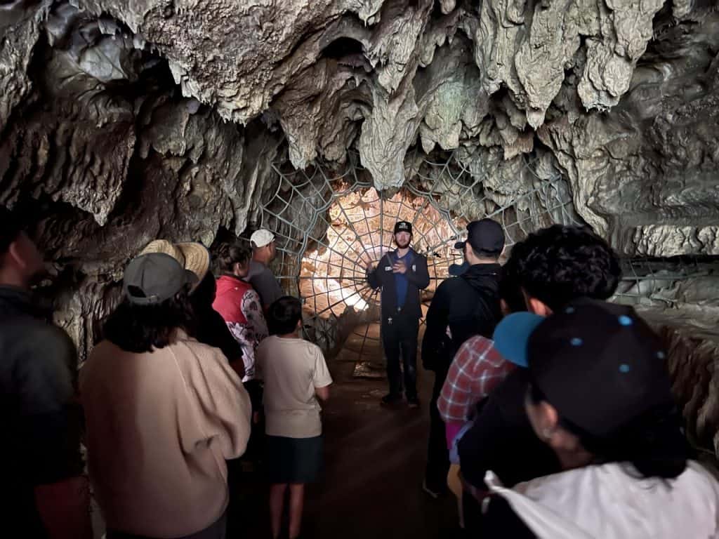 Tour guide and tour group standing at the front of the entrance to the Crystal Cave.