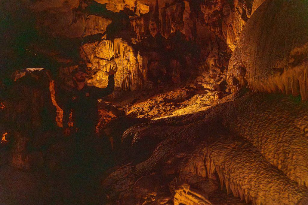 Tour guide standing in front of a cave formation on the tour.