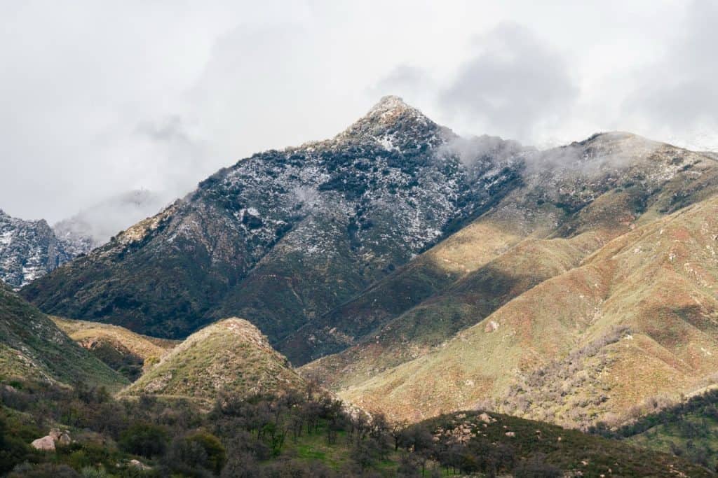 Mountain landscape with snow-capped peaks and rolling green hills in the Foothills region of Sequoia.
