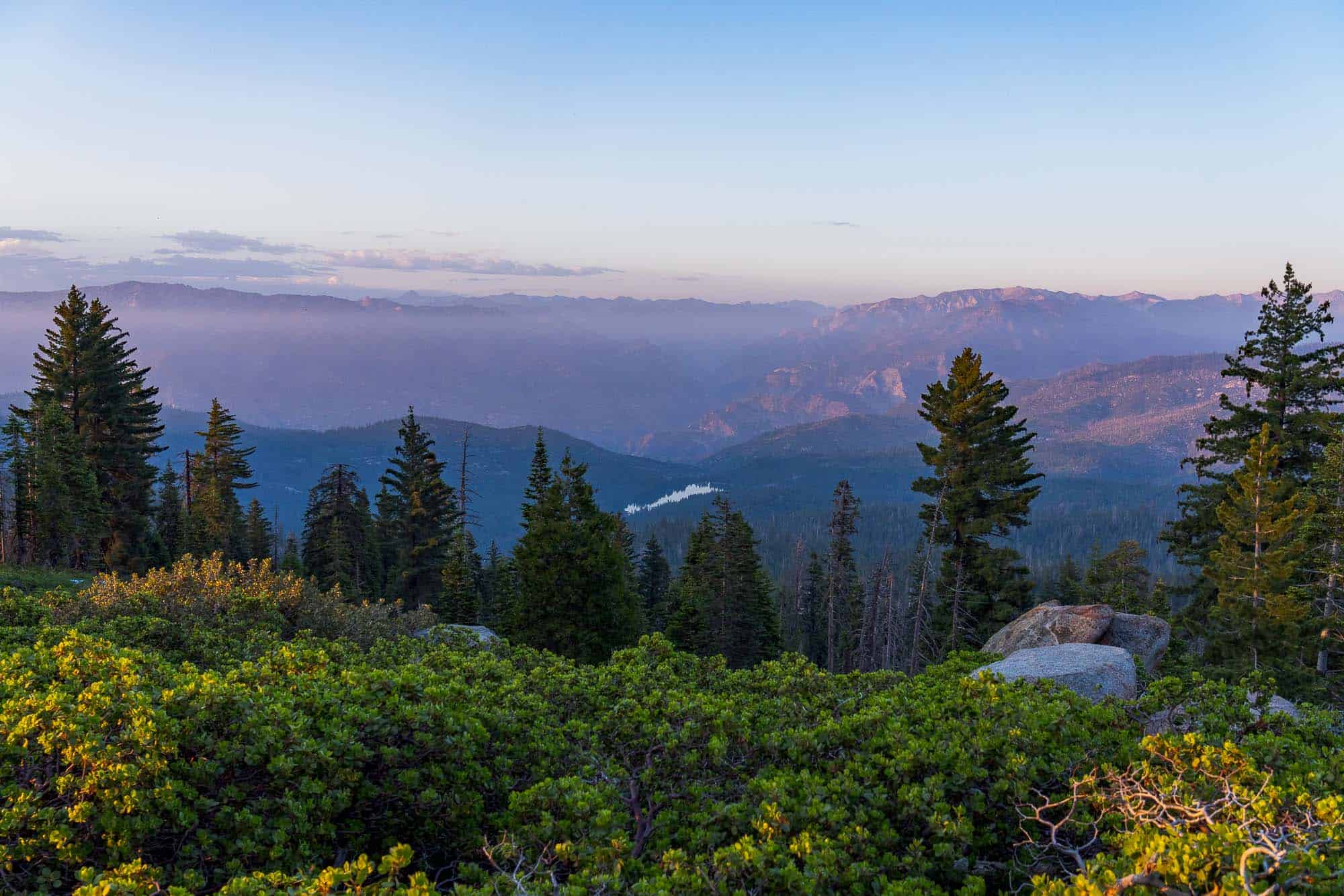 Panoramic view of Kings Canyon with mountains and forest at sunset.